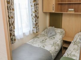 A bedroom with two single beds plants patterned bedding and floral curtains at Ocean View in Combe Martin