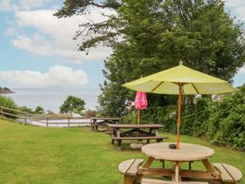 Picnic tables with umbrellas on a grassy area near trees with a sea view at Ocean View in Combe Martin