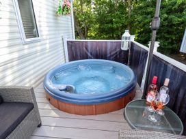 An outdoor deck with a hot tub table with wine bottles and glasses and outdoor seating at 25 Kingfisher Court in Tattershall