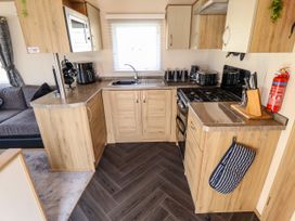 A kitchen with wooden cabinets a gas stove a microwave a sink and various appliances at 25 Kingfisher Court in Tattershall