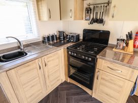 A kitchen with a gas stove, sink, countertop appliances, utensils, and wooden cabinets at 25 Kingfisher Court in Tattershall