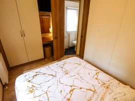 A bedroom with a double bed next to a wardrobe and a door leading to a bathroom at 25 Kingfisher Court in Tattershall