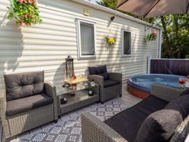 An outdoor seating area with wicker chairs a glass table and a hot tub at 25 Kingfisher Court in Tattershall