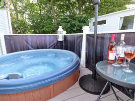 A hot tub on a deck with a glass table holding two bottles and three wine glasses at 25 Kingfisher Court in Tattershall