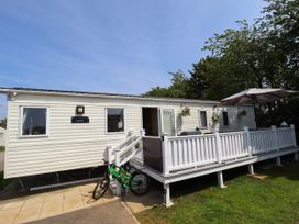A white mobile home with a porch railing a green bicycle and an umbrella at 25 Kingfisher Court in Tattershall