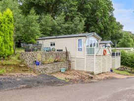A mobile home with a small fence and chairs outside near trees at The Boathouse in St Leonards-On-Sea