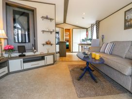 A living room with a gray sofa and blue coffee table next to a dining table with plants at The Boathouse in St Leonards-On-Sea