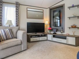 A living room with a sofa a TV on a corner cabinet and wall shelves at The Boathouse in St Leonards-On-Sea