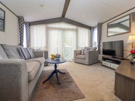 A living room with grey sofas a blue round coffee table and a television at The Boathouse in St Leonards-On-Sea