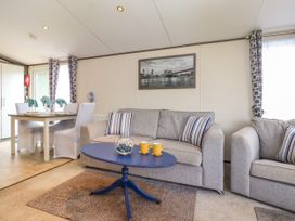 A living room with a gray sofa a blue coffee table two yellow mugs and a dining table with four chairs at The Boathouse in St Leonards-On-Sea