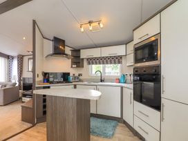 A kitchen with white cabinets a black oven microwave and stove with a window above the sink at The Boathouse in St Leonards-On-Sea