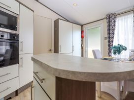 A kitchen with white cabinets a built in oven and microwave a countertop and a dining table with blue napkins at The Boathouse in St Leonards On Sea