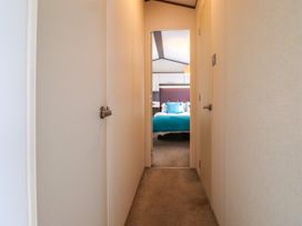 A hallway with doors on each side leading to a bedroom with a bed and pillows at The Boathouse in St Leonards-On-Sea