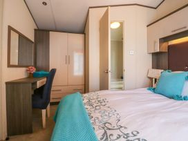 A bedroom with a bed a desk with a chair a wardrobe and an open door showing a bathroom at The Boathouse in St Leonards-On-Sea