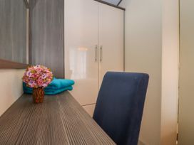 A desk with a small flower arrangement and folded towels next to a blue chair and a white wardrobe in a room at The Boathouse in St Leonards On Sea