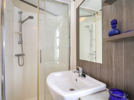 A bathroom with a shower enclosure and a sink with a faucet and mirror at The Boathouse in St Leonards-On-Sea
