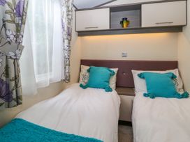 A bedroom with two single beds with teal pillows and a floral curtain at The Boathouse in St Leonards On Sea