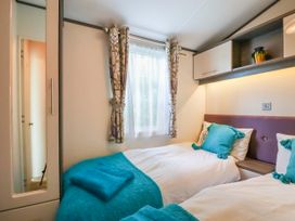 A bedroom with two single beds blue pillows and blankets floral curtains and a wardrobe at The Boathouse in St Leonards-On-Sea