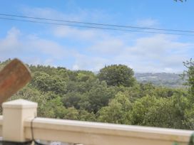 A view of a forest with various trees under a blue sky with some clouds seen over a balcony railing at The Boathouse in St Leonards-On-Sea