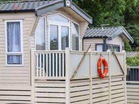 A beige mobile home with a porch railing holding wooden oars and an orange lifebuoy at The Boathouse in St Leonards-On-Sea
