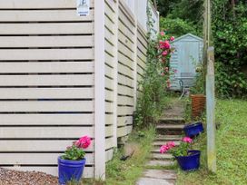 A garden path with pink flowers in blue pots leading to a blue wooden shed at The Boathouse in St Leonards-On-Sea