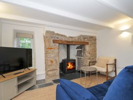 A living room with a television and wood stove at Sunrise Cottage in St Kew Highway near Wadebridge