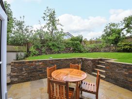 A garden with a wooden table and chairs at Sunrise Cottage in St Kew Highway near Wadebridge