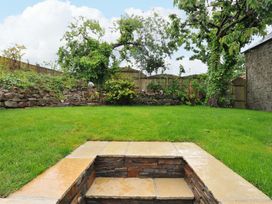 A garden with grass and a stone wall at Sunrise Cottage St Kew Highway near Wadebridge