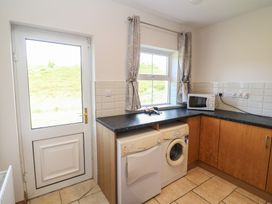 A kitchen with a washing machine and microwave at The Skating Rock in Bunane near Kenmare, County Kerry