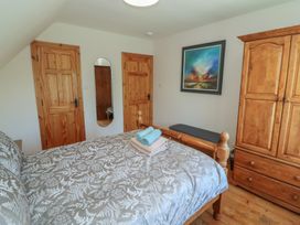 A bedroom with a bed, wardrobe, and mirror at The Skating Rock in Bunane near Kenmare, County Kerry