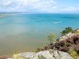 A view of water and boats from a rocky area at Northwood Lodge in Llanbedrog