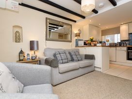 A living room with a sofa and kitchen area at Dolls Cottage in Looe