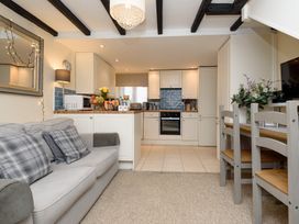 A living room with kitchen area and dining table at Dolls Cottage in Looe