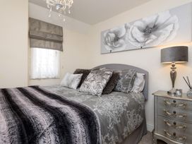 A bedroom featuring a bed with decorative pillows and a bedside table with a lamp at Dolls Cottage Looe