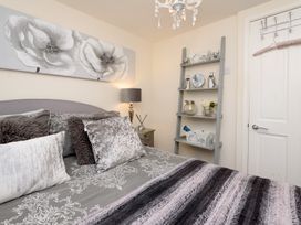 A bedroom with a bed and decorative shelf at Dolls Cottage in Looe