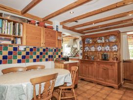 A kitchen with a dining table and wooden cabinets at Temple House in Goonhavern