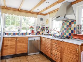 A kitchen with wooden cabinets and colorful tiles at Temple House in Goonhavern