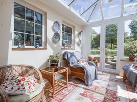 A conservatory with a sofa and plants at Temple House Goonhavern