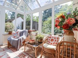 A conservatory with rattan furniture and plants at Temple House in Goonhavern