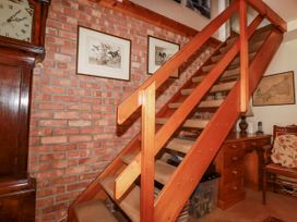 A staircase with wooden railing and wall art at Temple House in Goonhavern