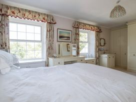 A bedroom with a bed and two windows at Temple House in Goonhavern