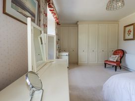 A bedroom with a wardrobe and a mirror at Temple House in Goonhavern