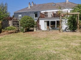 A garden with a house, deck, and seating area at Temple House in Goonhavern