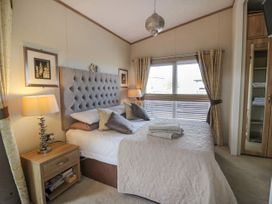 A bedroom with a bed with pillows and folded towels bedside tables with lamps framed pictures on the walls window with curtains and blinds and a wardrobe with mirror at 1 Fishermans Hill in Glenluce