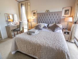 A bedroom with a double bed with pillows and folded towels bedside tables and lamps and a dressing table with a mirror at 1 Fishermans Hill in Glenluce