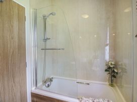 A bathroom with a bathtub shower combo glass screen and a flower vase on the tub edge at 1 Fishermans Hill in Glenluce