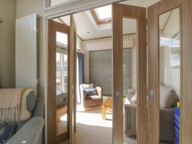 A living area with two armchairs a sofa and a wooden coffee table behind folding wooden doors at 1 Fishermans Hill in Glenluce