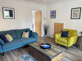 A living room with a blue sofa and yellow armchair at Plain Sailing in Weymouth