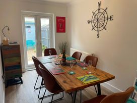 A dining room with a wooden table and chairs at Plain Sailing in Weymouth