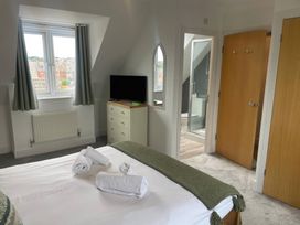 A bedroom with a bed, television, and en-suite bathroom at Plain Sailing in Weymouth